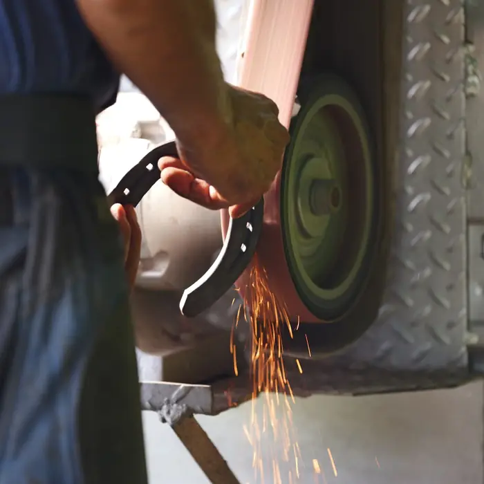 Shaping a horseshoe on the grinder