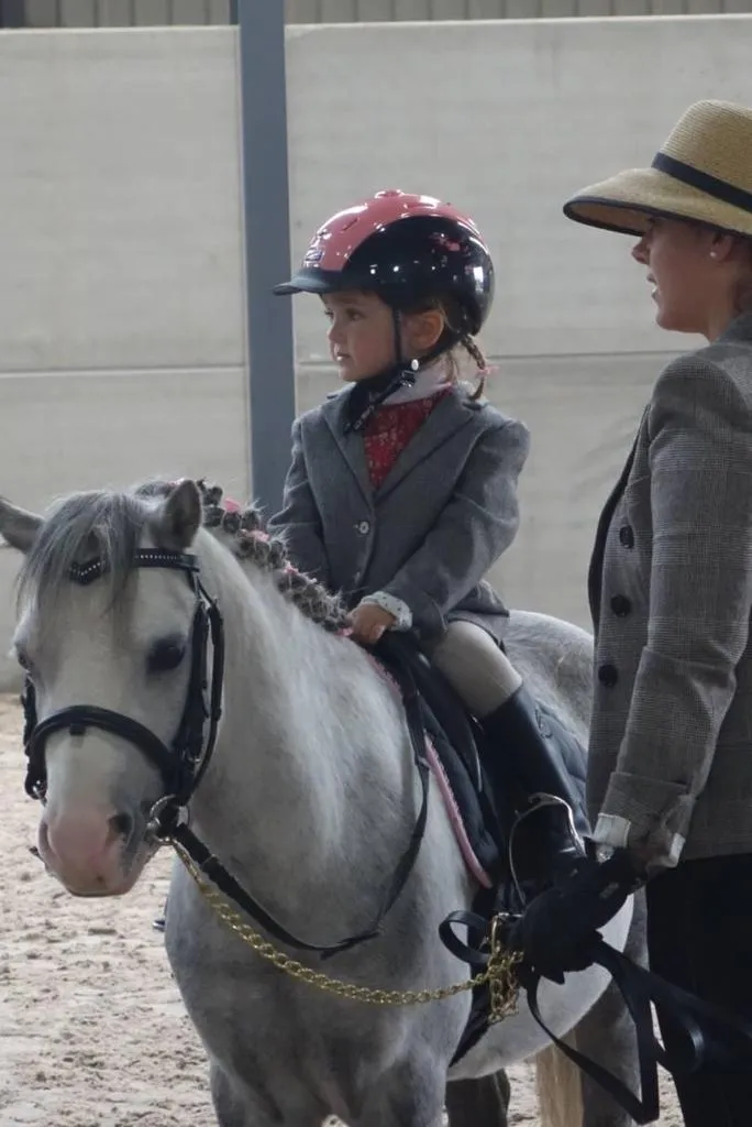 Instructor coaching a rider during a flatwork lesson in the arena at L'Écurie Equestrian Club