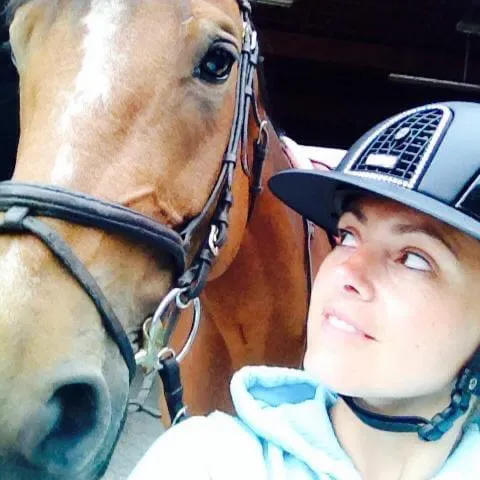 Rider in show attire preparing her horse before a lesson at L'Écurie Equestrian Club